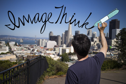 ImageThink graphic recording company office opens up in San Francisco. Photo of the back of Senior Graphic Recorder James Lake lifting up & cartoon marker & writing the ImageThink logo over the skyline of san francisco. He's on a tall hill in a park, the city & water in the distance.