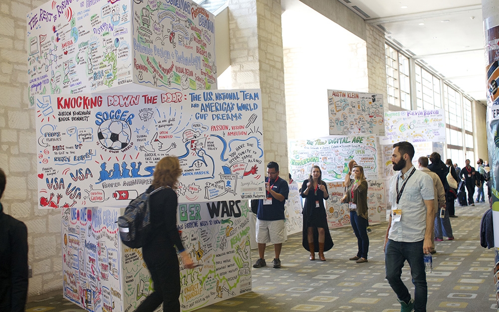 conference attendees walk around imagethink's graphic recording tower display at the 2015 sxsw conference in austin texas