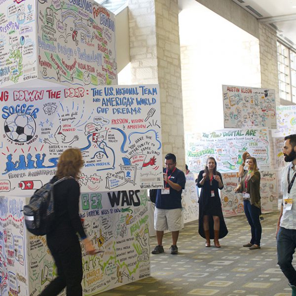 conference attendees walk around imagethink's graphic recording tower display at the 2015 sxsw conference in austin texas