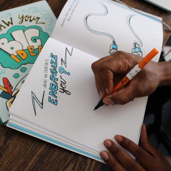 Picture of A Person Writing In A Copy Of Draw Your Big Idea
