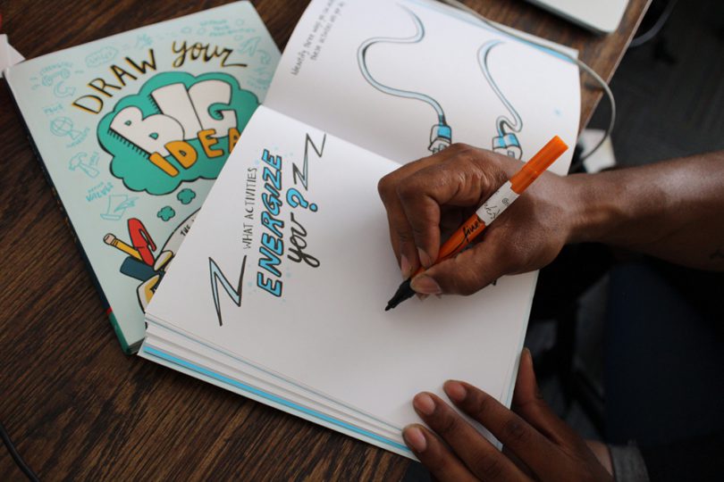 Picture of A Person Writing In A Copy Of Draw Your Big Idea