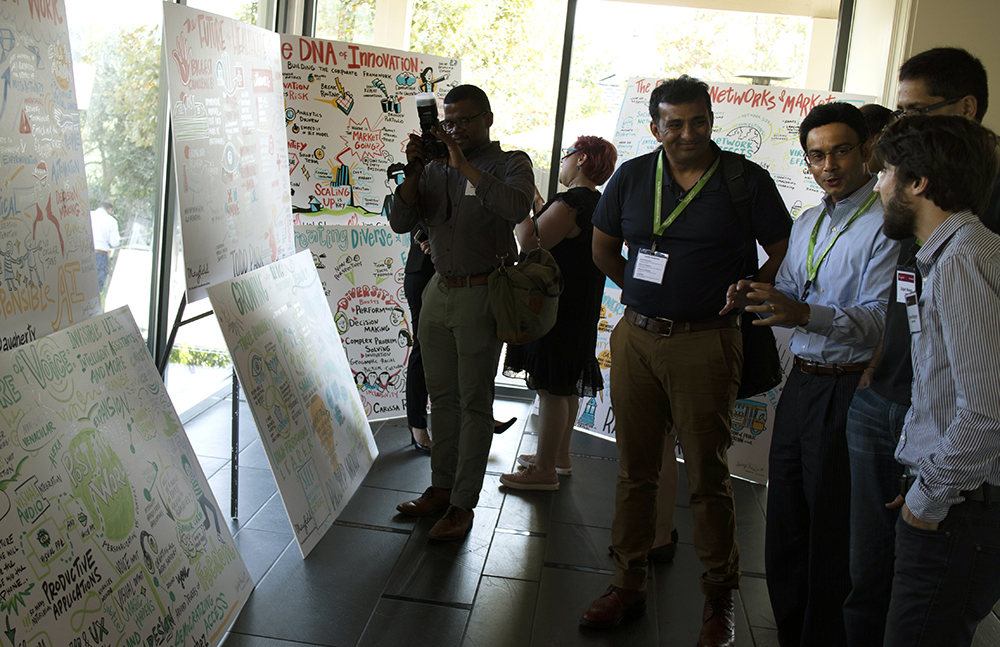 Tradeshow attendees take pictures of ImageThink graphic recording boards.