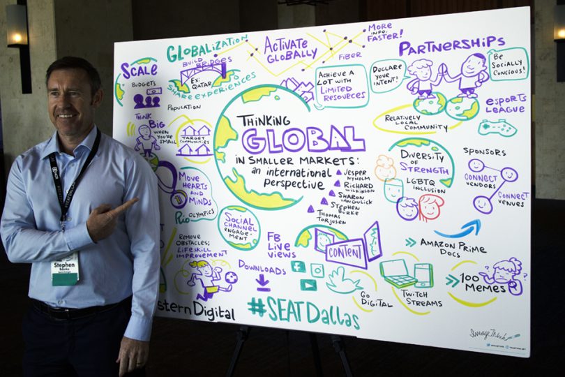 Man posing next to an infographic mural