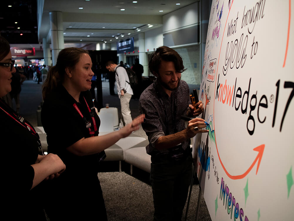 a graphic recorder from imagethink draws on a whiteboard at a technology conference