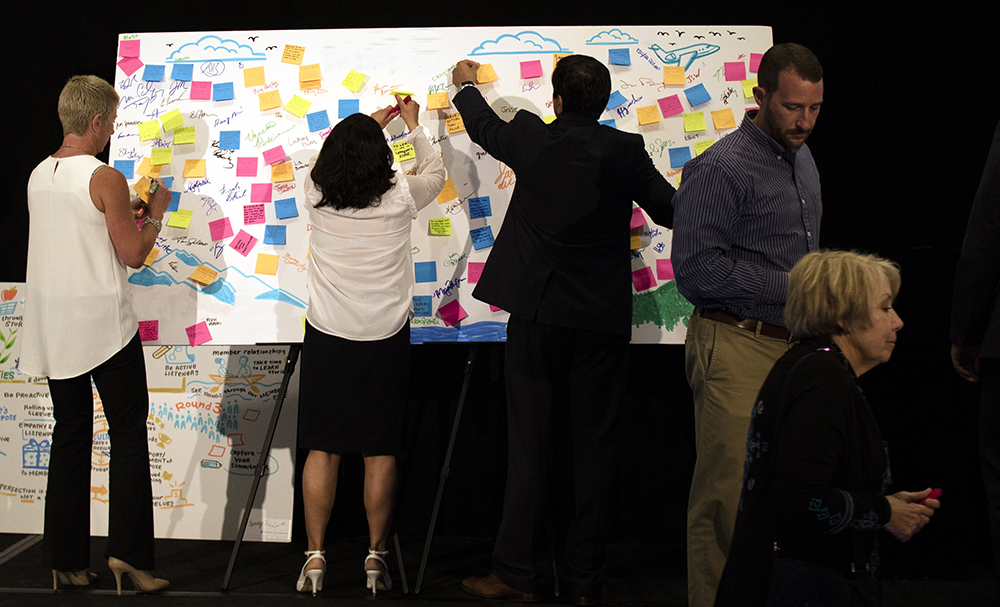 meeting attendees use a whiteboard illustration from imagethink to vote on new ideas and prioritize strategies.