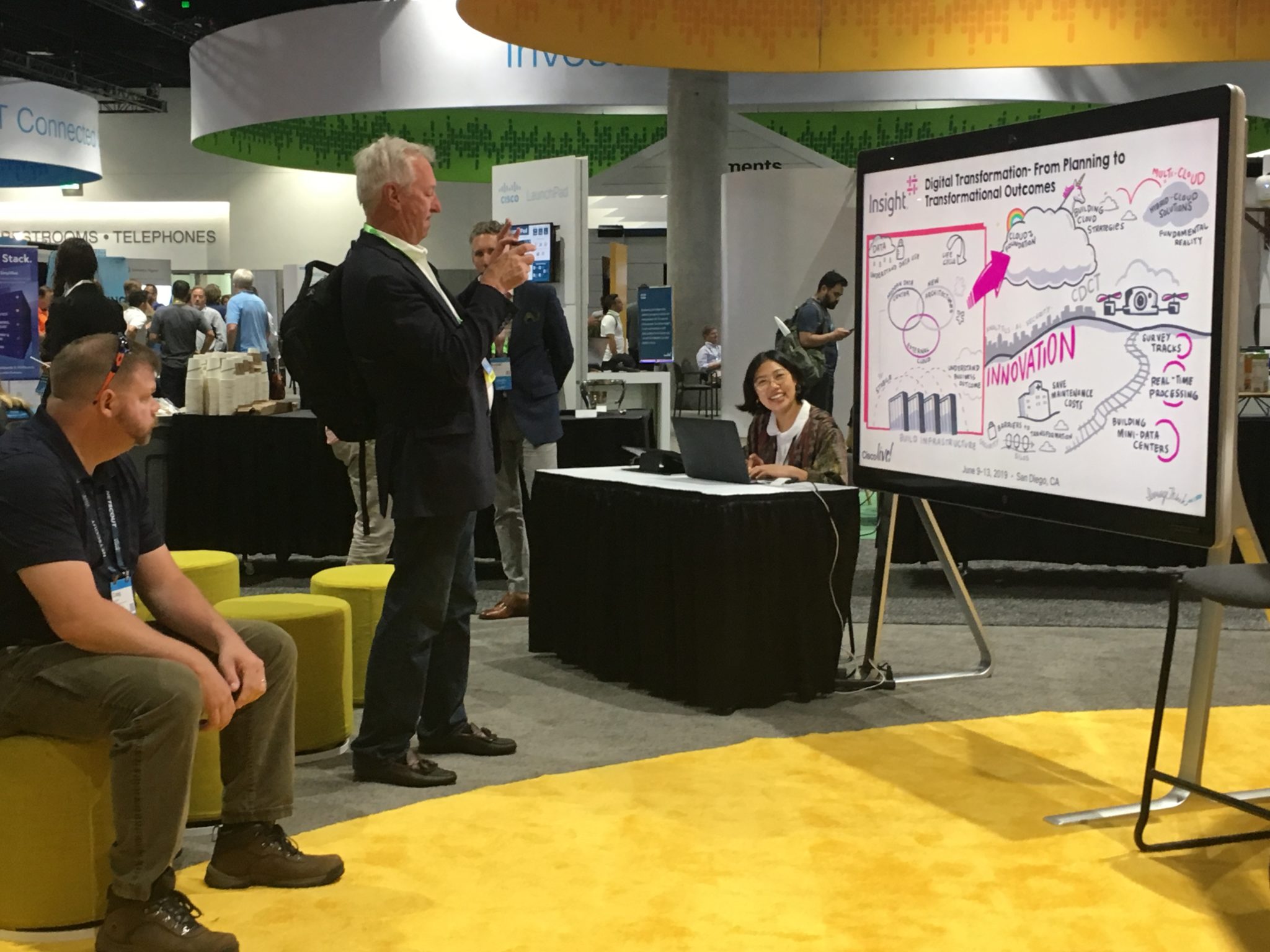 Cisco Live! attendee photographing a digital graphic recording of a session on a Cisco WebeX board