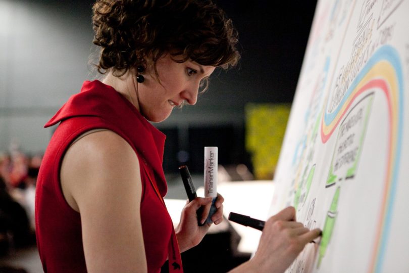 An image of ImageThink CEO Nora Herting drawing on a board.