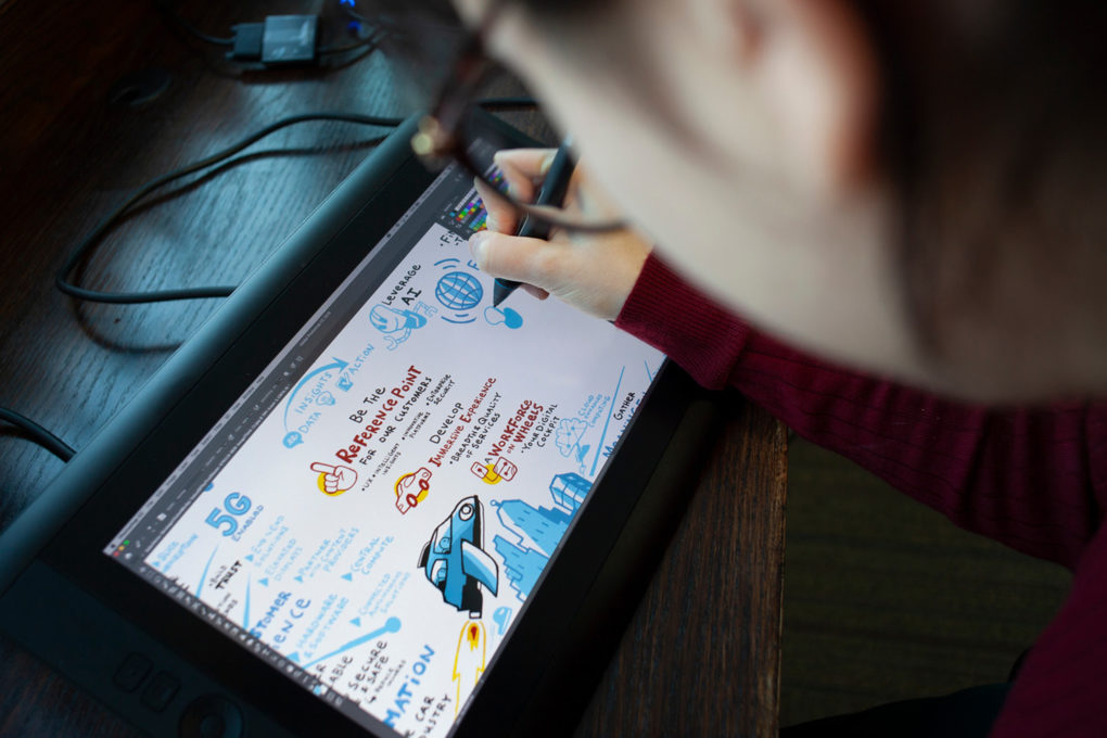 A graphic recorder working digitally in-studio on a clients remote meeting using a Wacom Cintiq drawing tablet.
