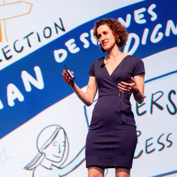 ImageThink Founder and CEO Nora Herting delivering a keynote speech on the value of visuals in front of a large scaled graphic recording for WBENC.