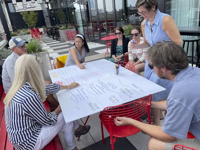 ImageThink visual strategist leading a graphic‑facilitated retreat with a college communications team, capturing brand themes and strategy on a large illustrated board.