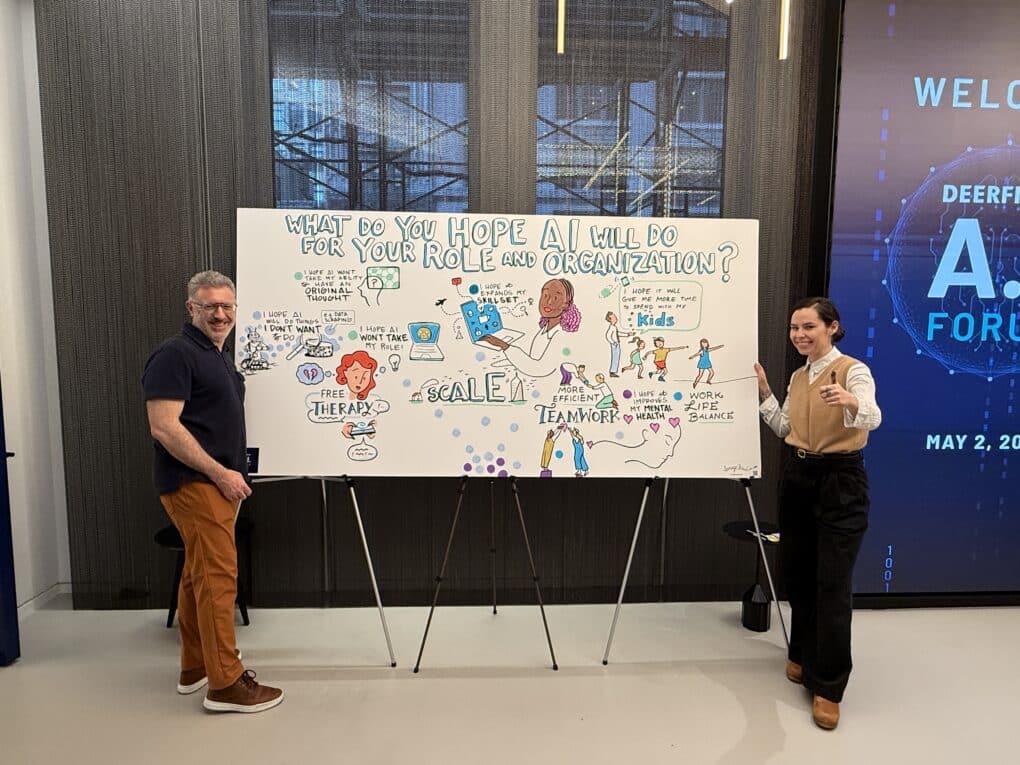 Two event participants pose beside an ImageThink visual notes social listening mural about AI at a healthcare summit in Manhattan, New York City.