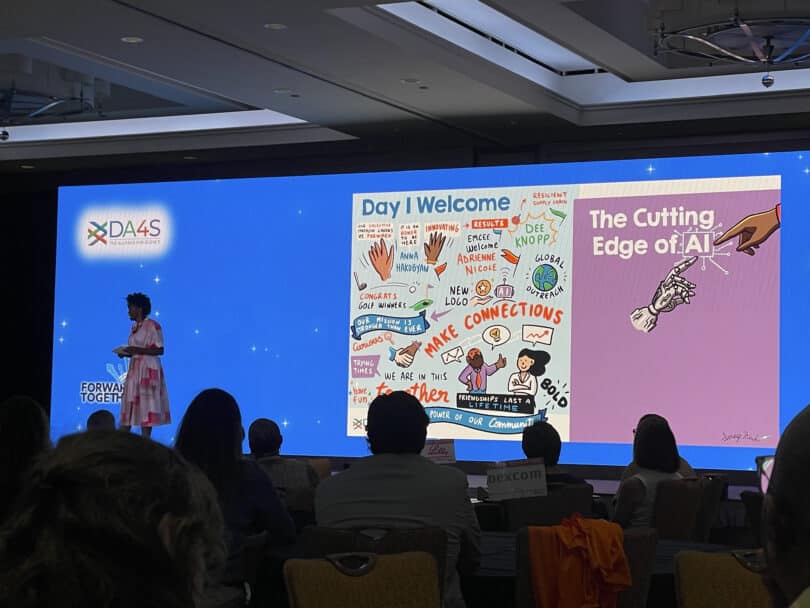 Attendees view a projected graphic recording of conference welcome notes and AI theme at a life sciences meeting.