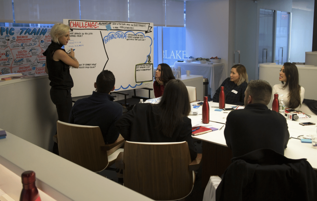 A graphic recorder illustrates key ideas on a large board during a healthcare conference session.