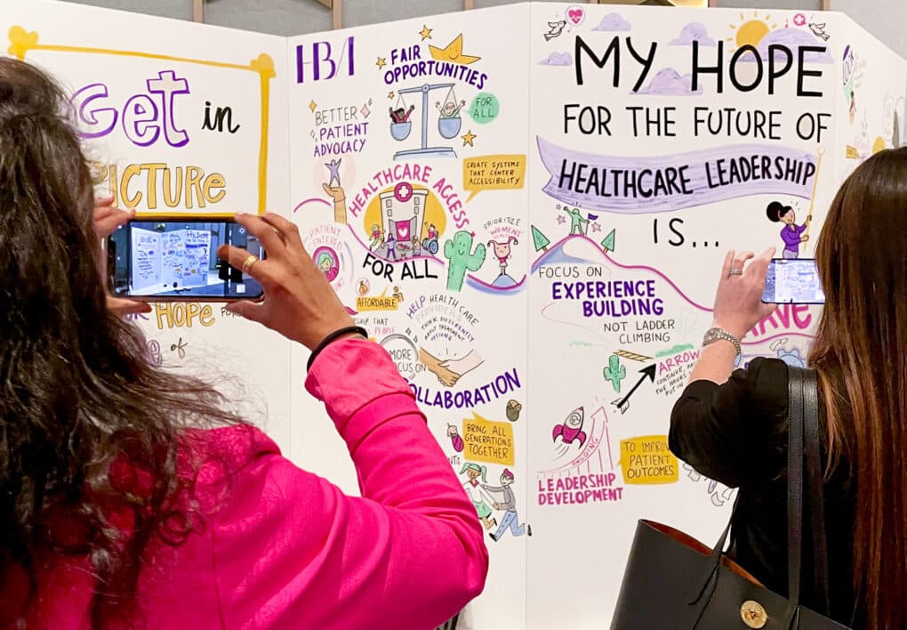 participants take pictures at Health Care Business Women's conference of a social listening mural