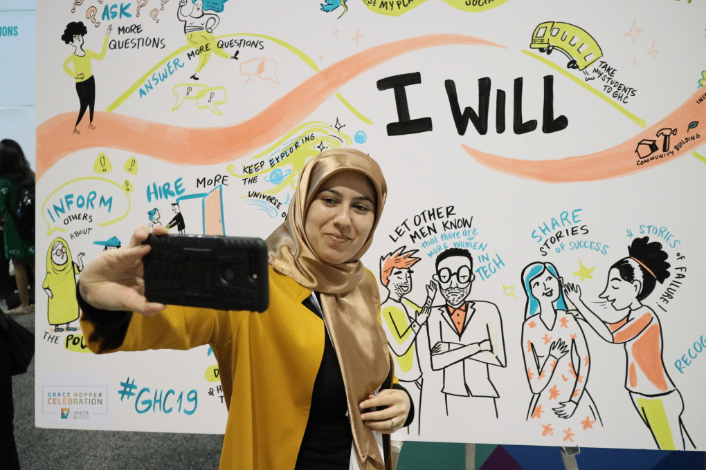 A woman capturing ideas on a colorful graphic recording event board.